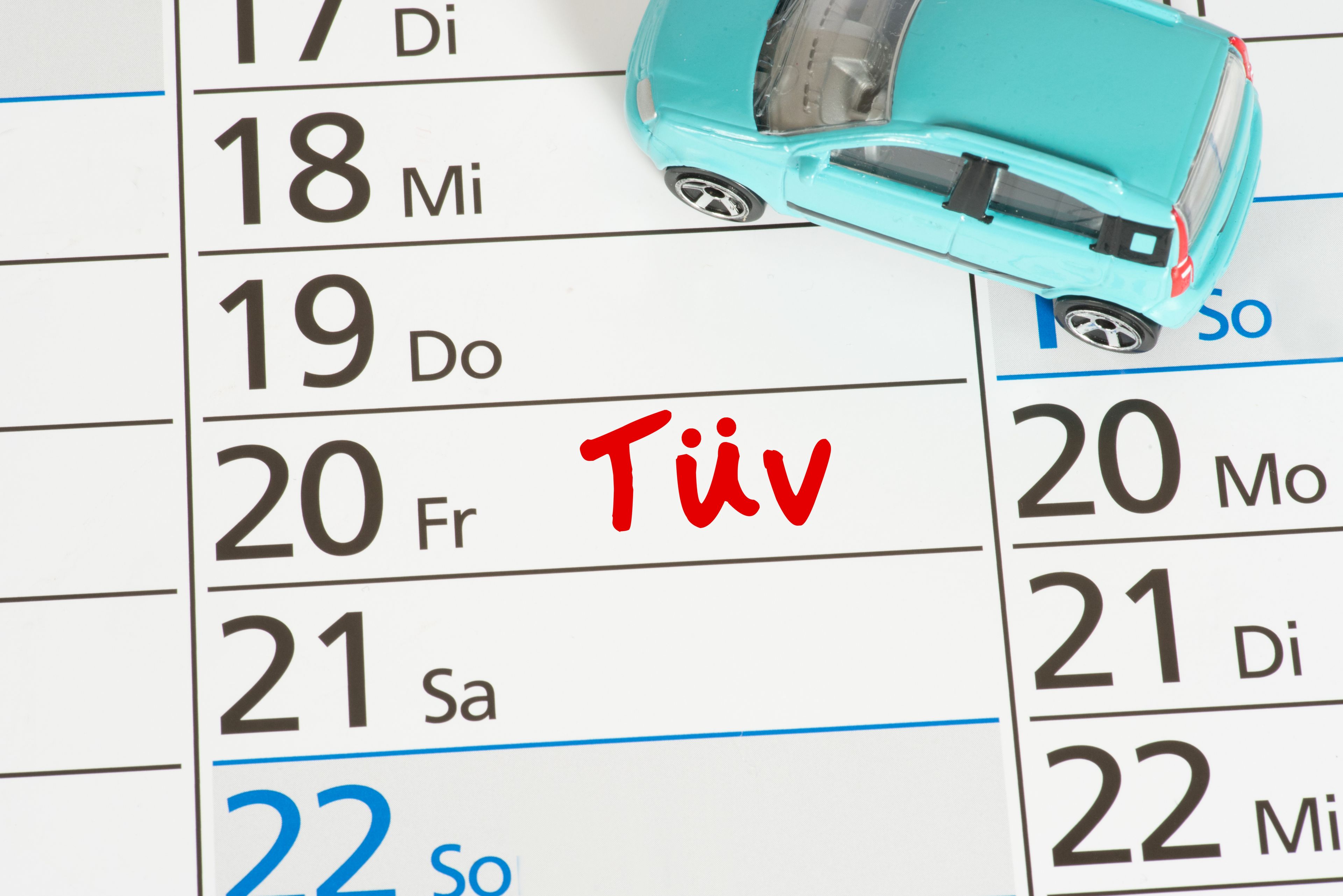 Bild zeigt einen Terminkalender mit kleinem Spielzeugauto auf dem ein TÜV Termin eingetragen ist.