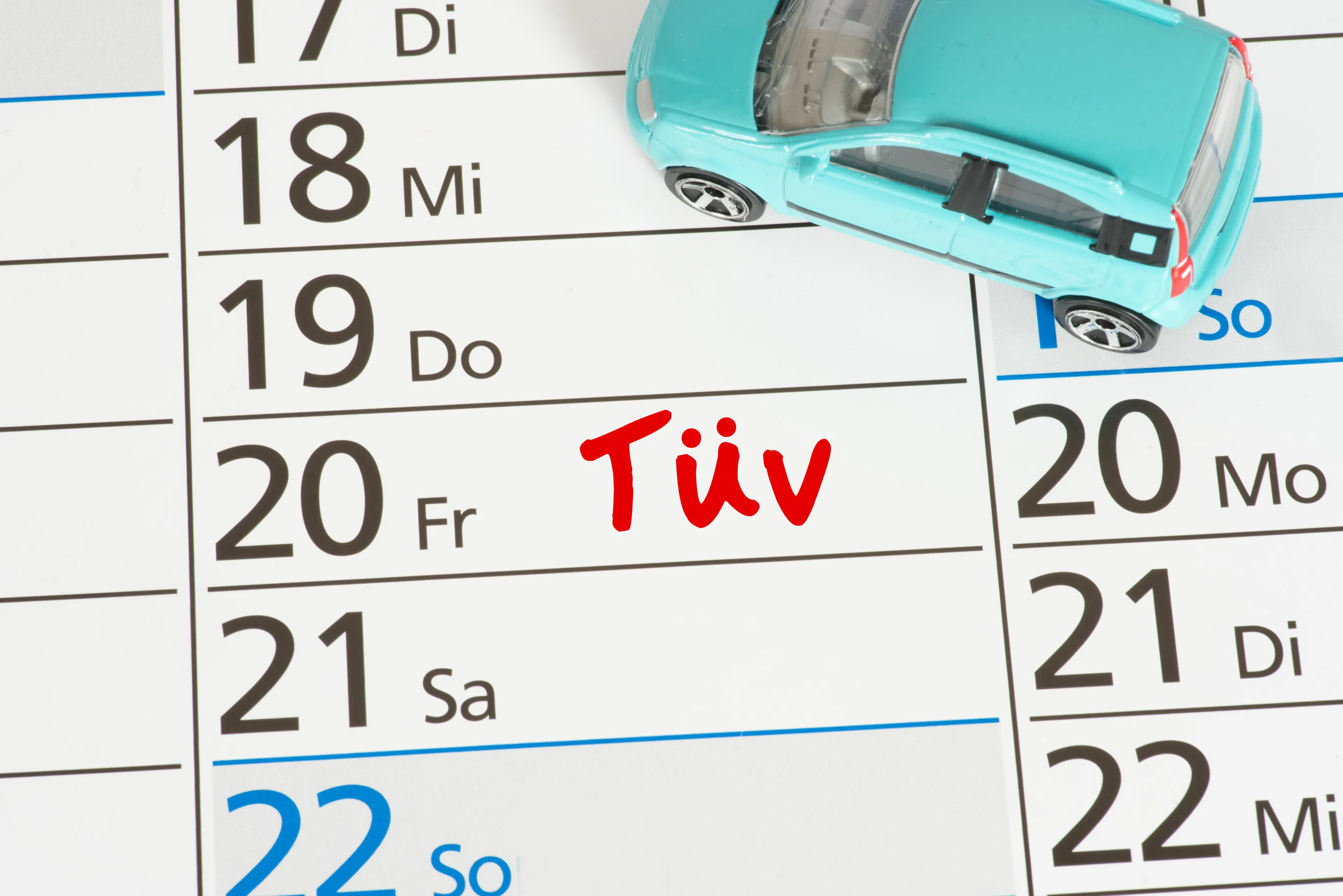 Bild zeigt einen Terminkalender mit kleinem Spielzeugauto auf dem ein TÜV Termin eingetragen ist.