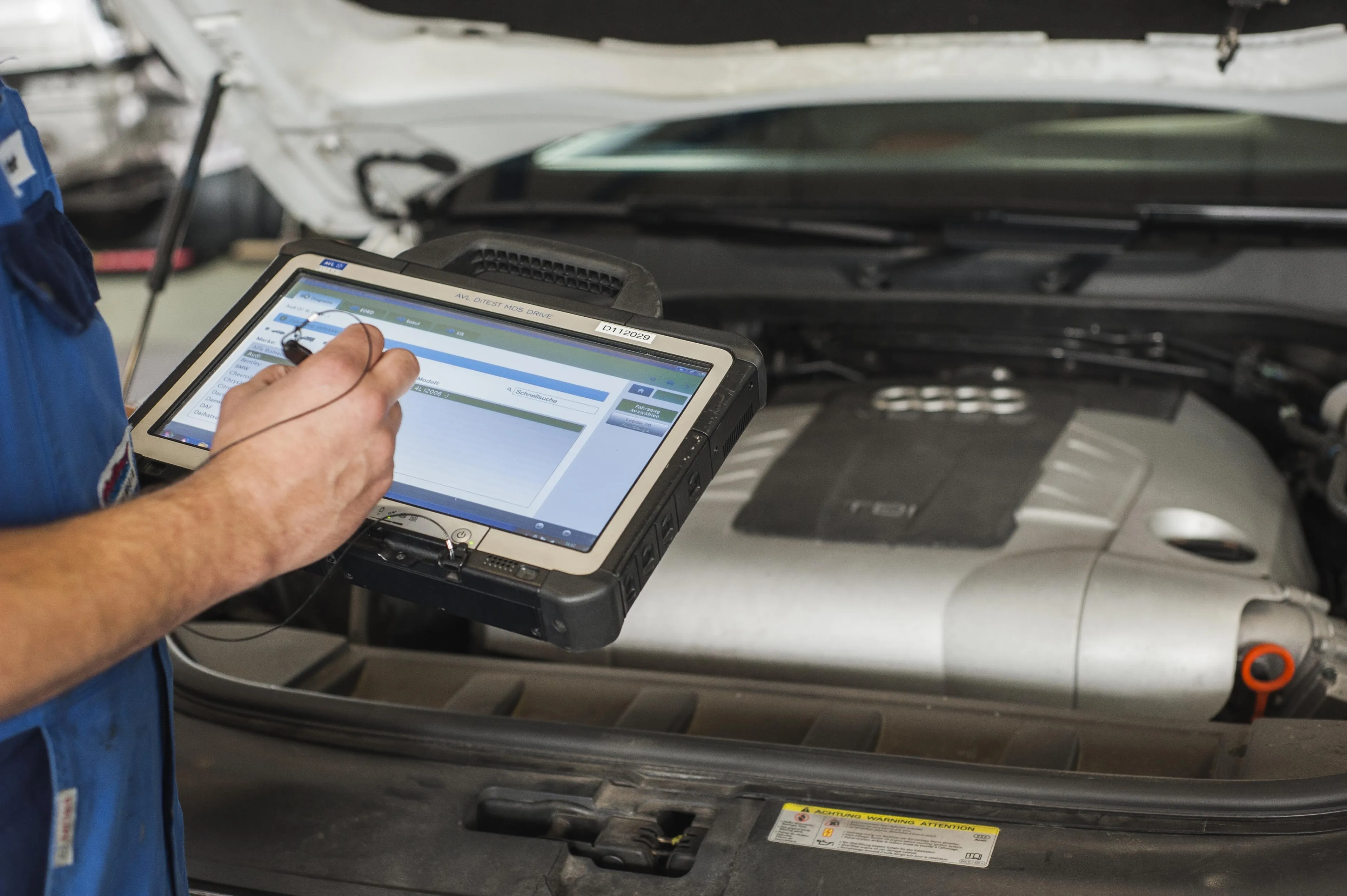 Autotechniker jat ein Auto an sein Prüfmonitor angeschlossen und wählt Marke und Modell aus.