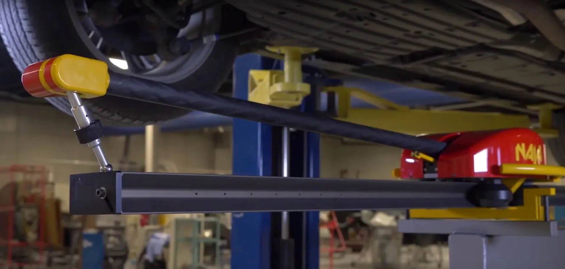 Auf dem Bild ist ein Fahrzeug auf einer Hebebühne zu sehen, dessen Karosserie mittels des NAJA Systems in allen Einzelheiten vermessen wird.